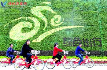 市民騎公共自行車路過(guò)市人民廣場(chǎng)一處花壇。記者 張馳